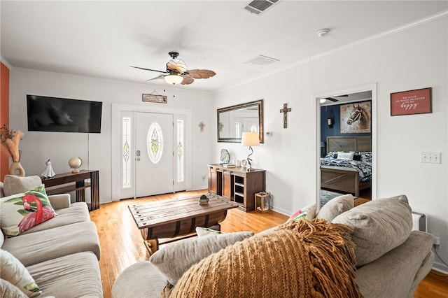 living room with visible vents, a ceiling fan, light wood-style flooring, and crown molding