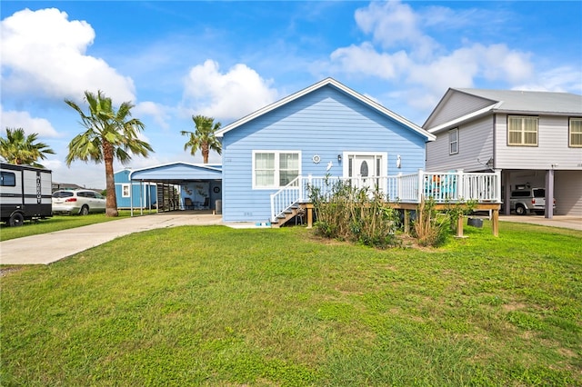 back of house featuring concrete driveway, a yard, a wooden deck, and a carport