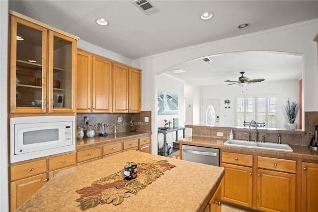 kitchen featuring visible vents, white microwave, arched walkways, tasteful backsplash, and a sink
