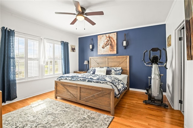 bedroom featuring crown molding, baseboards, a ceiling fan, and wood finished floors