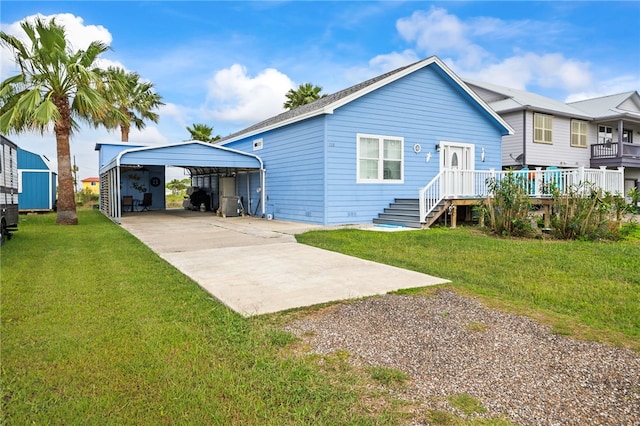 back of property with a detached carport, a yard, and concrete driveway