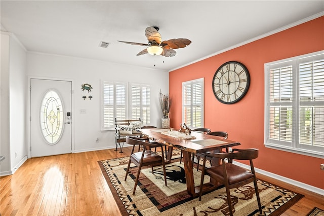 dining space featuring crown molding, light wood-style flooring, a ceiling fan, baseboards, and visible vents