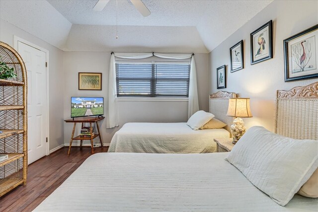 bedroom with a textured ceiling, dark wood-type flooring, ceiling fan, and vaulted ceiling