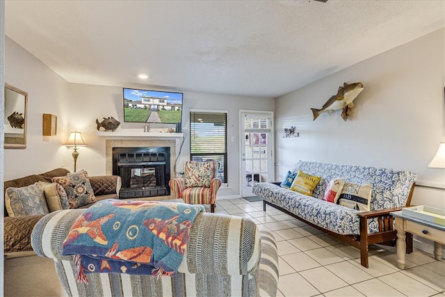 living room with a textured ceiling, a tiled fireplace, and light tile patterned floors