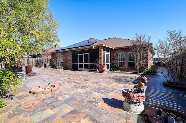 back of property featuring a patio area, solar panels, and a sunroom