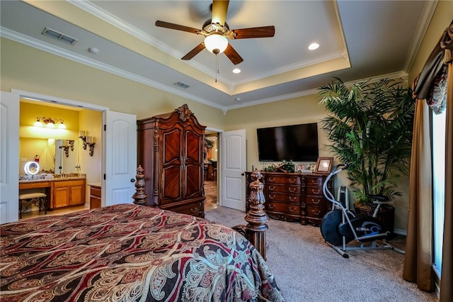 carpeted bedroom with a raised ceiling, ensuite bath, ceiling fan, and ornamental molding