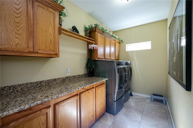 clothes washing area with washer and clothes dryer, light tile patterned flooring, and cabinets