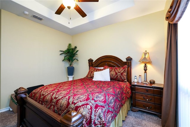 carpeted bedroom with ceiling fan and a tray ceiling