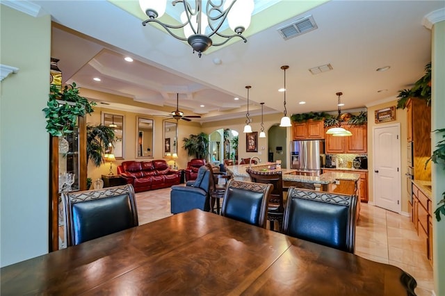 dining room with ceiling fan with notable chandelier, light tile patterned floors, a tray ceiling, and crown molding