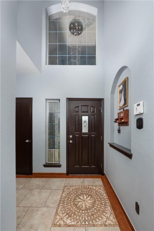 tiled foyer featuring a high ceiling and an inviting chandelier