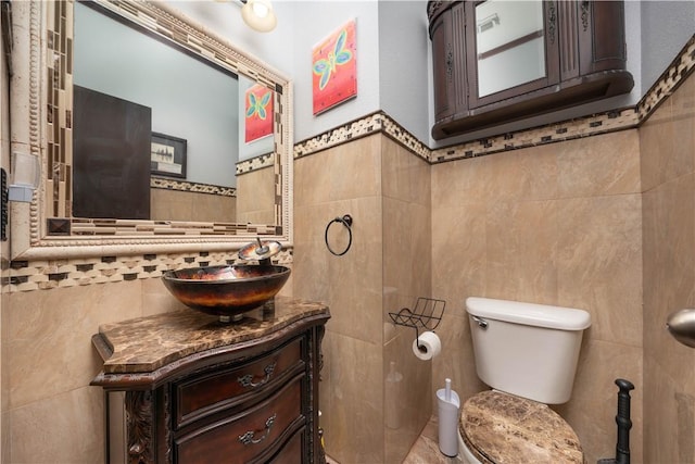 bathroom with vanity, toilet, and tile walls