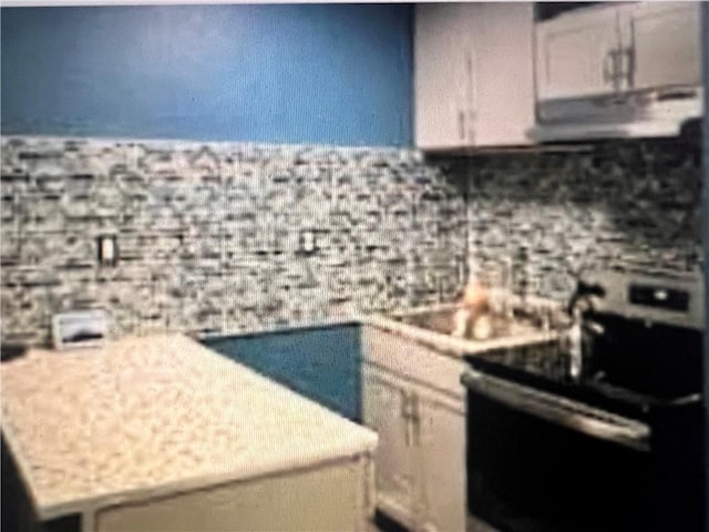 kitchen featuring light stone countertops and stainless steel range with electric cooktop