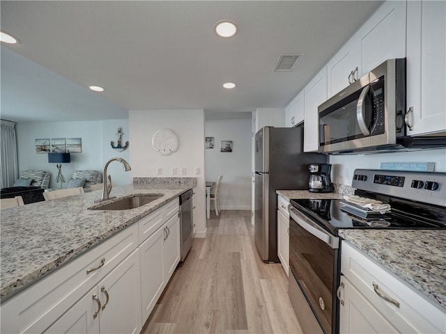 kitchen featuring stainless steel appliances, light stone countertops, sink, white cabinets, and light hardwood / wood-style flooring