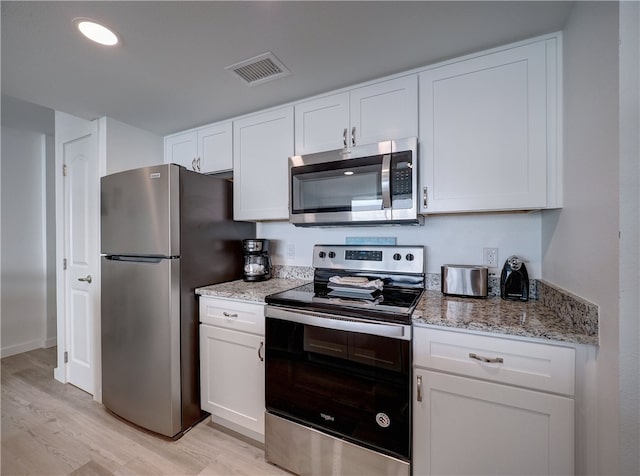 kitchen with white cabinets, light stone counters, light hardwood / wood-style flooring, and appliances with stainless steel finishes