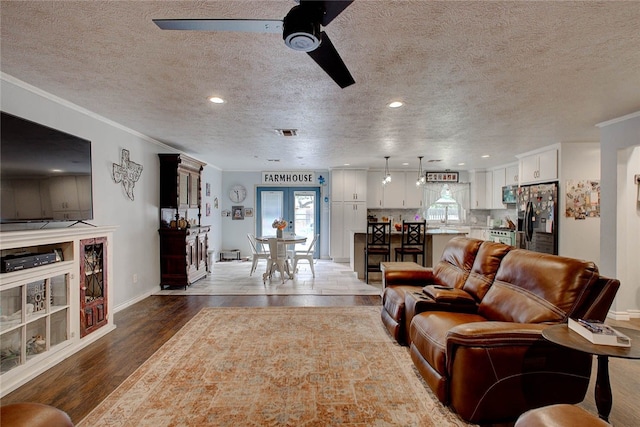 living room with ceiling fan, french doors, crown molding, hardwood / wood-style floors, and a textured ceiling