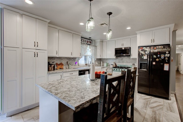 kitchen with light stone countertops, black appliances, decorative light fixtures, a center island, and white cabinetry