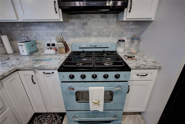 kitchen featuring high end stove, white cabinetry, light stone countertops, and exhaust hood