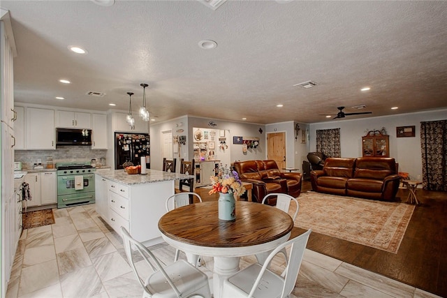 dining space with ceiling fan, light wood-type flooring, and a textured ceiling