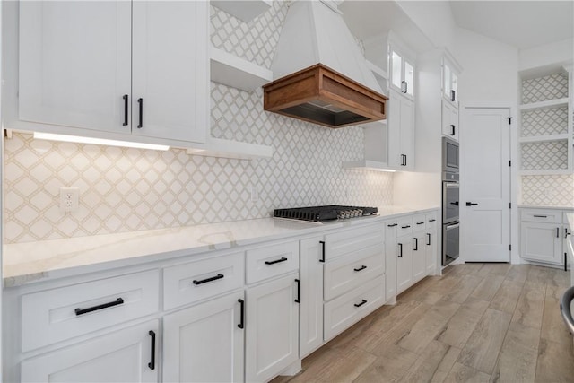 kitchen with light hardwood / wood-style floors, stainless steel appliances, light stone countertops, custom range hood, and white cabinetry