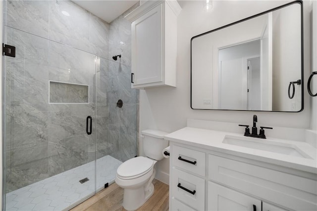 bathroom featuring a shower with shower door, toilet, vanity, and wood-type flooring