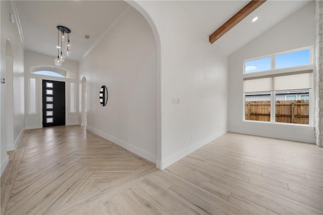 entryway featuring a towering ceiling, ornamental molding, and beam ceiling