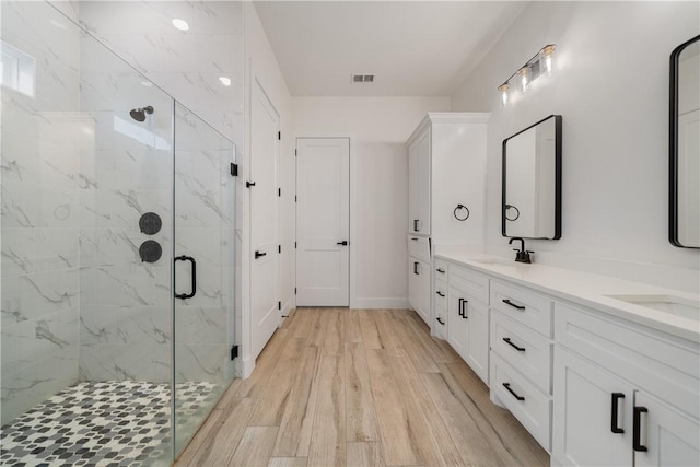 bathroom with vanity, a shower with shower door, and hardwood / wood-style flooring