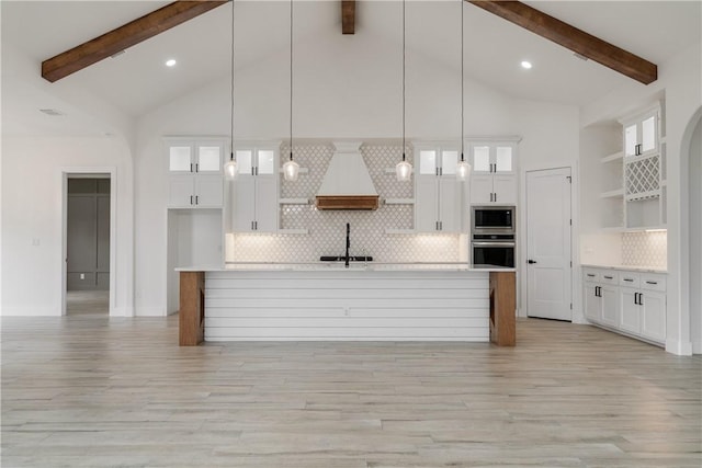 kitchen with decorative light fixtures, custom range hood, white cabinetry, and appliances with stainless steel finishes