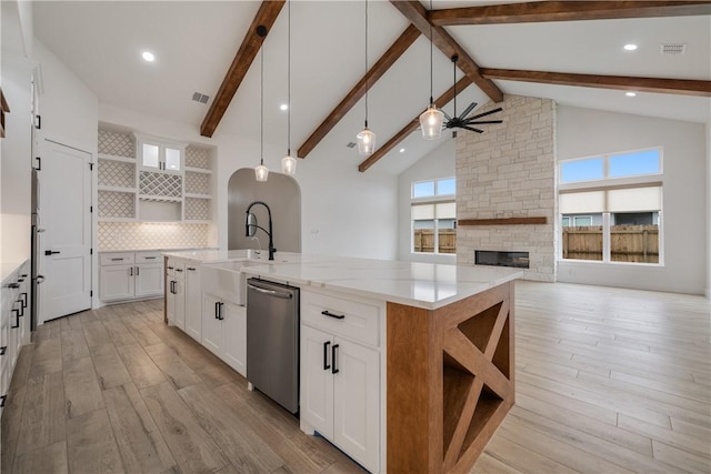 kitchen with light stone countertops, dishwasher, decorative light fixtures, high vaulted ceiling, and white cabinetry