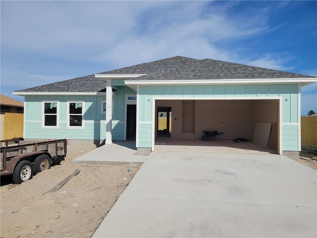 view of front of house featuring driveway, an attached garage, roof with shingles, and board and batten siding