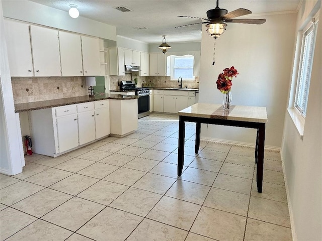 kitchen with white cabinetry, stainless steel gas range oven, light tile patterned floors, and backsplash