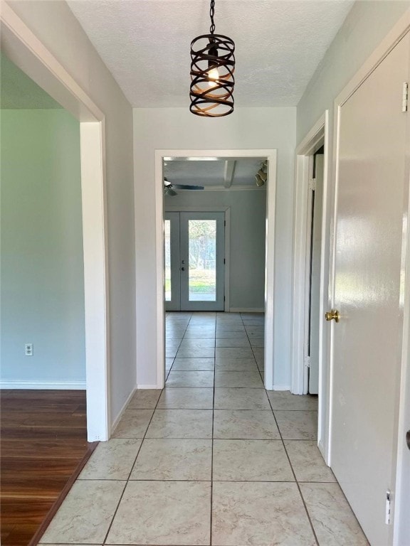 hallway with light tile patterned floors, french doors, and a textured ceiling