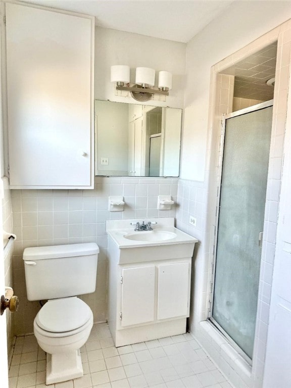 bathroom featuring vanity, a shower with shower door, toilet, and tile walls