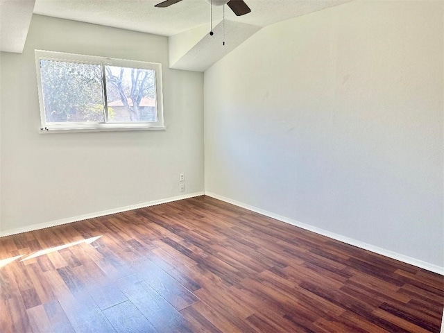 empty room with ceiling fan, lofted ceiling, dark wood-type flooring, and a textured ceiling