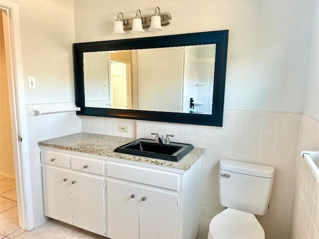 bathroom with tile patterned flooring, vanity, tile walls, and toilet