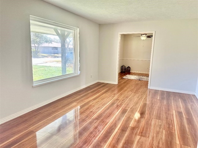 unfurnished room with ceiling fan, light hardwood / wood-style flooring, and a textured ceiling