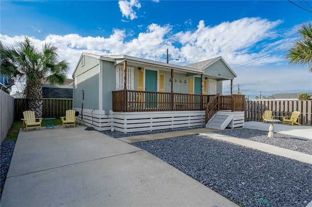 view of front facade featuring covered porch, fence, and a patio area