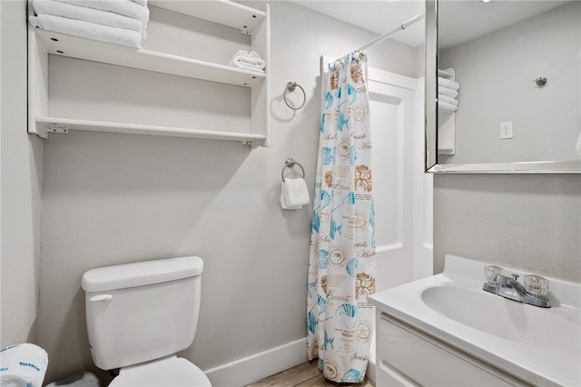 bathroom with curtained shower, toilet, vanity, wood finished floors, and baseboards