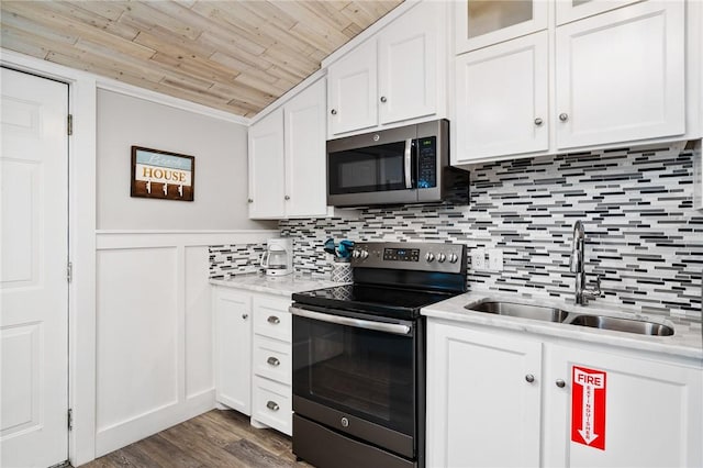 kitchen with stainless steel appliances, a sink, wood ceiling, white cabinetry, and dark wood finished floors