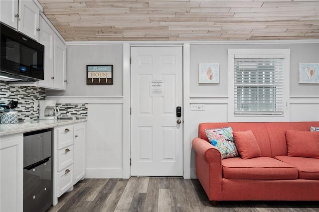 kitchen featuring dark wood-type flooring, black microwave, white cabinetry, and backsplash