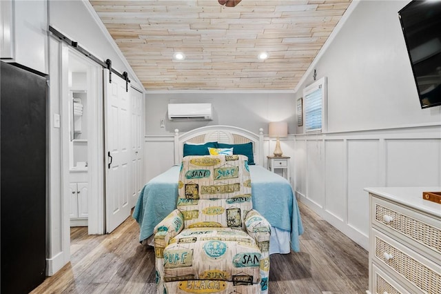 bedroom with a barn door, wooden ceiling, ornamental molding, a wall mounted air conditioner, and light wood-type flooring