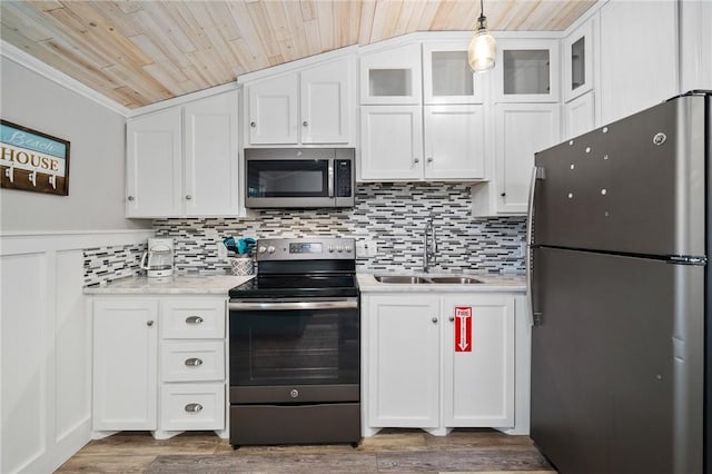 kitchen featuring glass insert cabinets, appliances with stainless steel finishes, white cabinets, and a sink