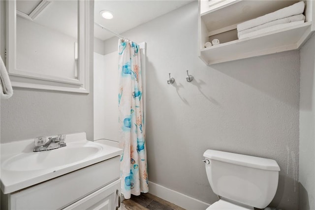 bathroom with baseboards, toilet, wood finished floors, curtained shower, and vanity