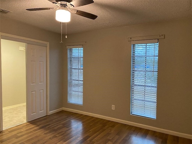 unfurnished room featuring ceiling fan, plenty of natural light, wood-type flooring, and a textured ceiling