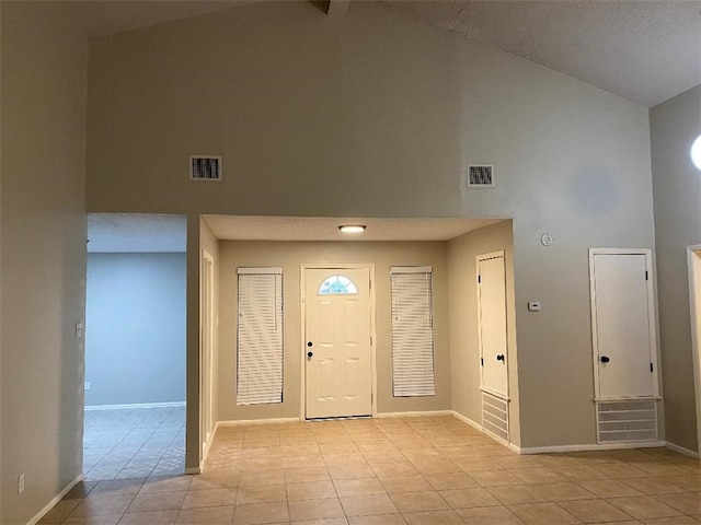 foyer entrance with beamed ceiling, light tile patterned floors, and high vaulted ceiling