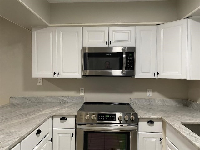 kitchen with light stone countertops, white cabinetry, and stainless steel appliances