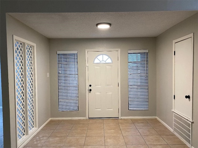 foyer entrance with light tile patterned floors and a textured ceiling