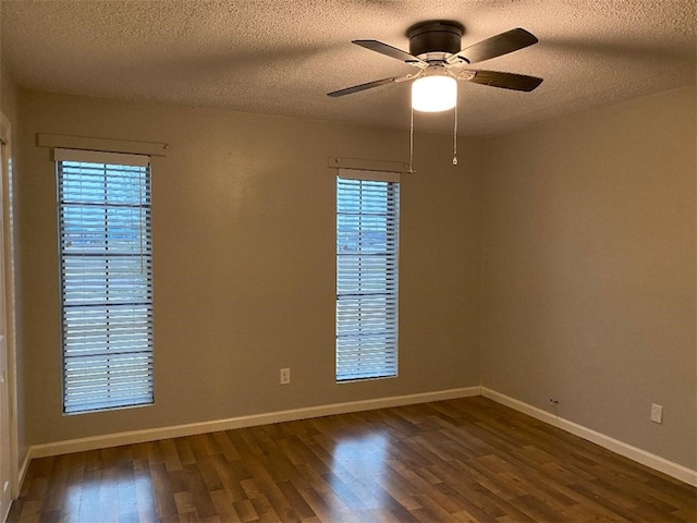 empty room with a textured ceiling, ceiling fan, plenty of natural light, and dark hardwood / wood-style floors