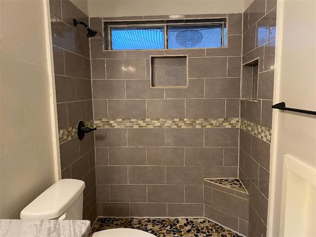 bathroom featuring toilet and a tile shower