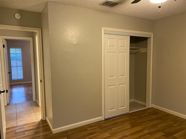 unfurnished bedroom featuring a textured ceiling, ceiling fan, dark wood-type flooring, and a closet