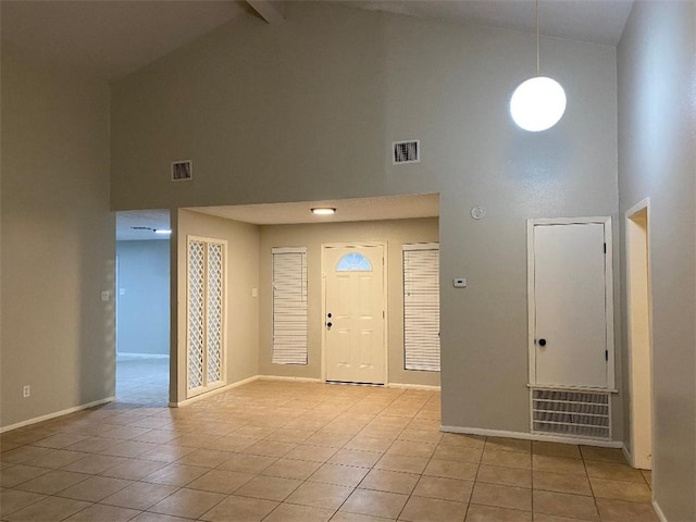 tiled foyer entrance with beamed ceiling and high vaulted ceiling